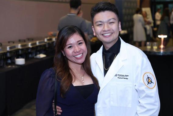 A Graduate of the Doctorate of Physical Therapy Prgram standing next to a woman at his graduation