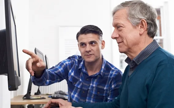One man training another man on computer