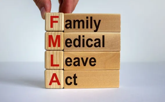 Image of hand holding blocks that spell out "family," "medical," "leave," and "act"