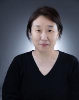 Professional photo of a woman with dark hair, black top, and neutral expression.